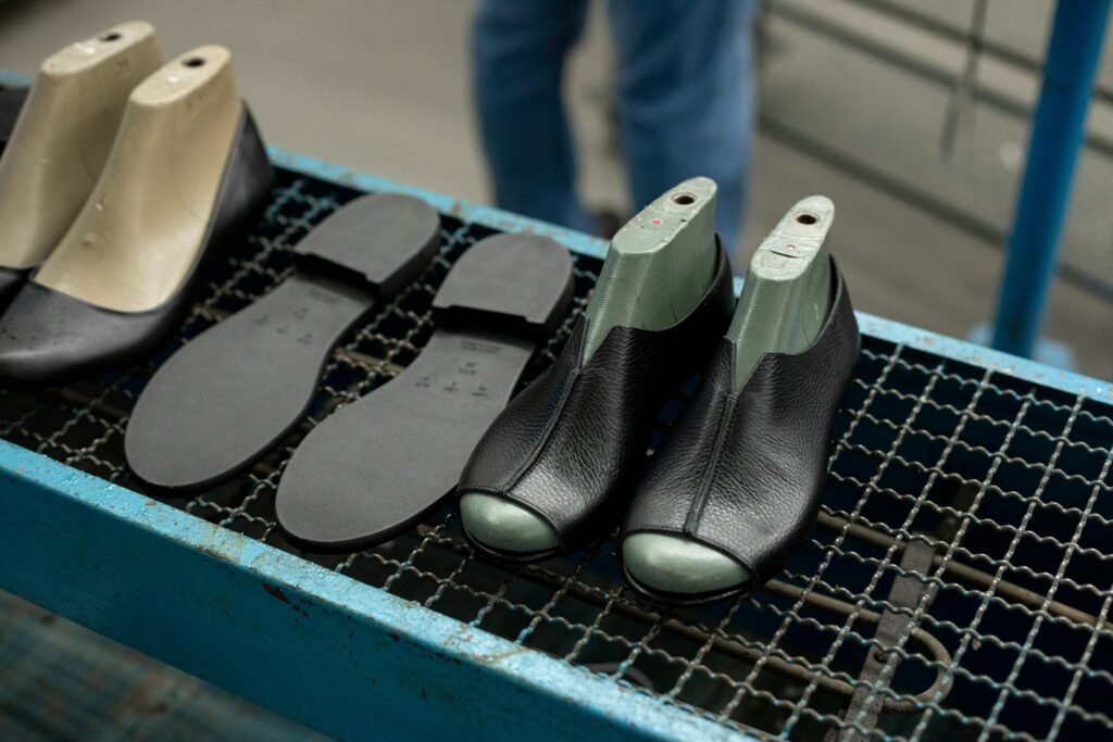 Detailed view of shoe making process with leather uppers and molds on work table.