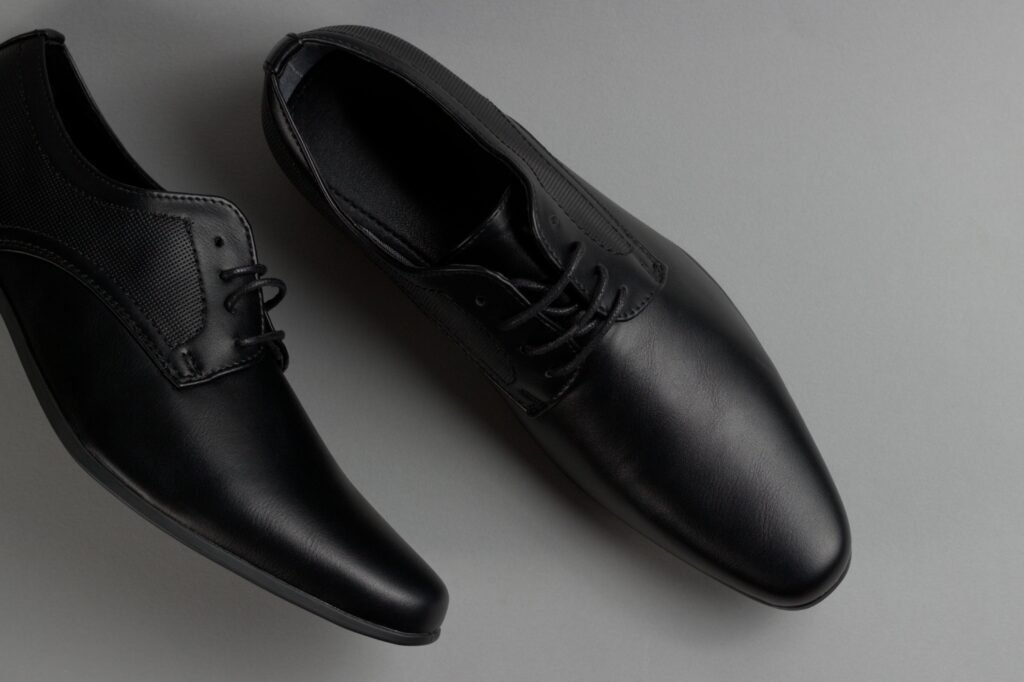 Pair of stylish black formal shoes displayed on a minimalist grey background, perfect for business attire.